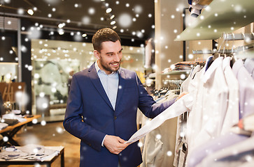 Image showing happy young man choosing clothes in clothing store