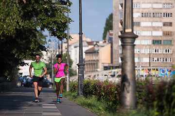 Image showing young smiling multiethnic couple jogging in the city