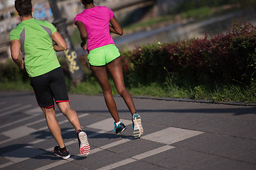 Image showing young smiling multiethnic couple jogging in the city