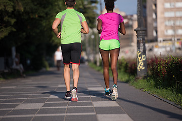 Image showing young smiling multiethnic couple jogging in the city