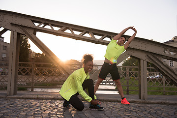 Image showing jogging couple warming up and stretching in the city