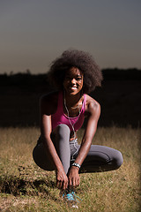 Image showing black woman runner tightening shoe lace