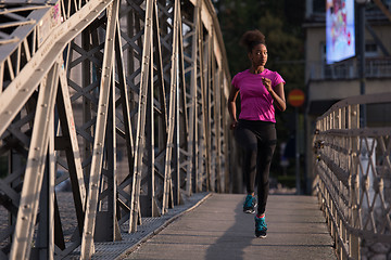 Image showing african american woman running across the bridge