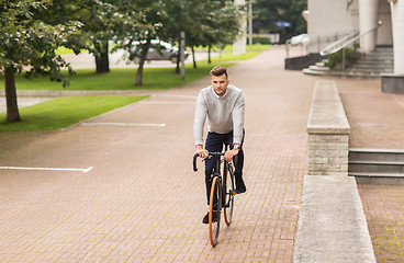 Image showing young man riding bicycle on city street