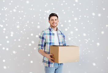 Image showing smiling young man with cardboard box at home
