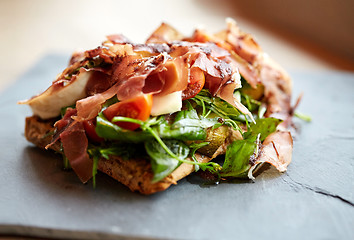 Image showing prosciutto ham salad on stone plate at restaurant