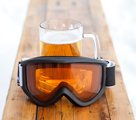 Image showing Ski goggles and glass mug with fresh cold beer