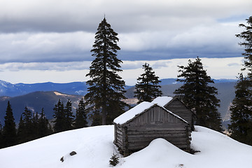 Image showing Old wooden hut in winter snow mountains at gray day