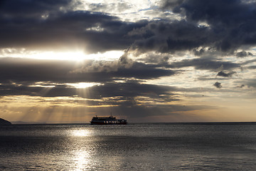 Image showing Sea with sea boat and gray sky with sun at sunset