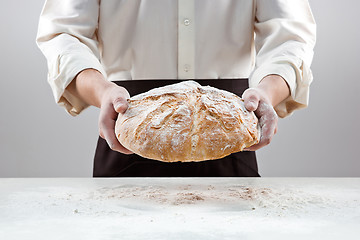 Image showing Baker man holding rustic organic loaf of bread in hands