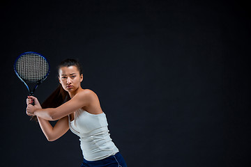 Image showing Portrait of beautiful girl tennis player with a racket on dark background