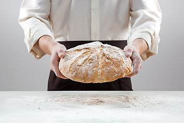 Image showing Baker man holding rustic organic loaf of bread in hands