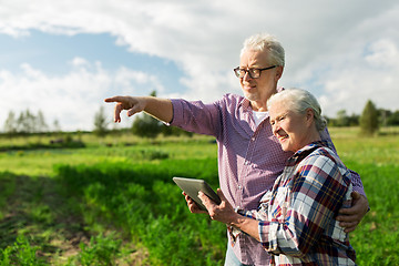 Image showing happy senior couple with tablet pc at summer farm