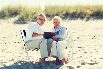 Image showing happy senior couple with tablet pc on summer beach