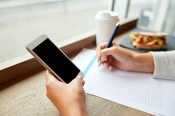 Image showing woman with smartphone and paper form at cafe