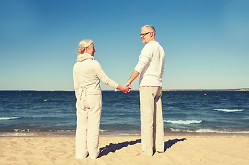 Image showing happy senior couple holding hands summer beach