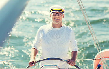 Image showing senior man at helm on boat or yacht sailing in sea