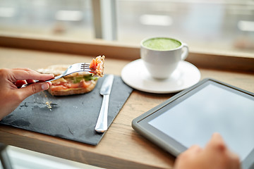 Image showing woman with tablet pc and panini sandwich at cafe