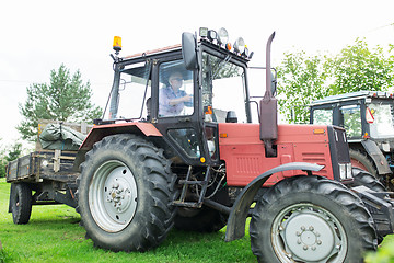 Image showing senior man driving tractor at farm