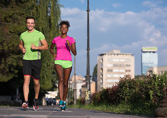 Image showing young smiling multiethnic couple jogging in the city