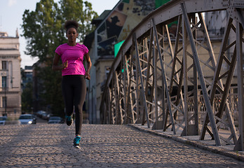 Image showing african american woman running across the bridge