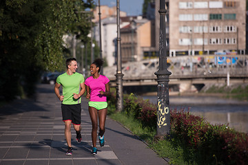 Image showing young smiling multiethnic couple jogging in the city