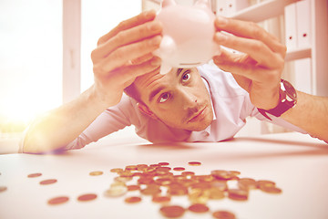 Image showing businessman with piggy bank and coins at office