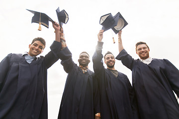 Image showing happy students or bachelors waving mortar boards