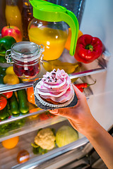 Image showing Woman takes the sweet cake from the open refrigerator