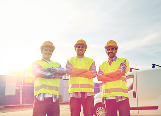 Image showing happy male builders in high visible vests outdoors