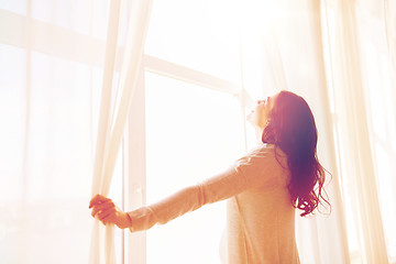 Image showing close up of pregnant woman opening window curtains