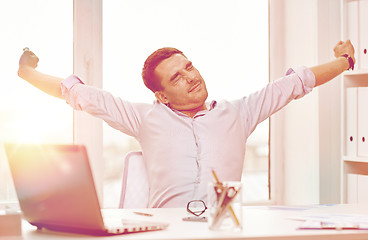 Image showing bored businessman with laptop and papers at office