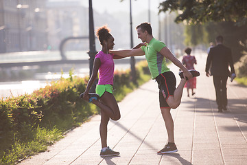 Image showing jogging couple warming up and stretching in the city