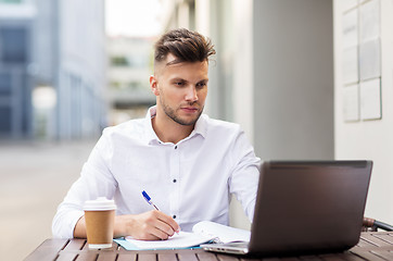 Image showing man with laptop and coffee at city cafe