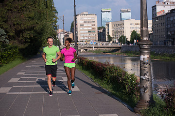 Image showing young smiling multiethnic couple jogging in the city