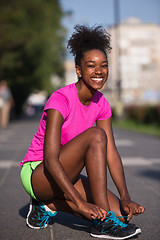 Image showing African american woman runner tightening shoe lace