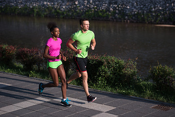 Image showing young smiling multiethnic couple jogging in the city