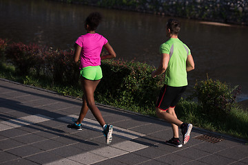 Image showing young smiling multiethnic couple jogging in the city