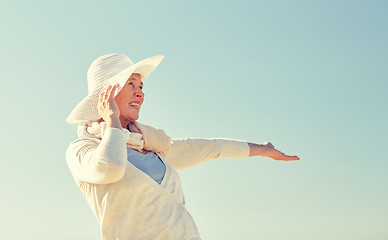 Image showing happy senior woman in sun hat over blue sky