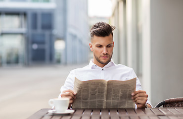 Image showing smiling man reading newspaper at city street cafe