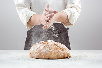 Image showing The male hands in flour and rustic organic loaf of bread