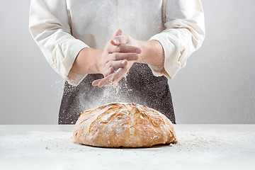 Image showing The male hands in flour and rustic organic loaf of bread