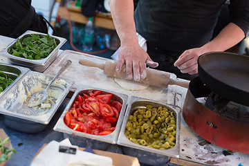 Image showing Chef making pita bread for falafel roll outdoor on street stall.