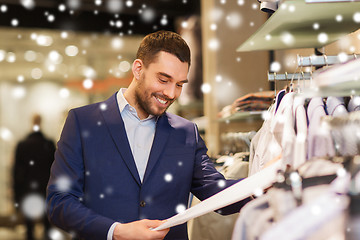 Image showing happy young man choosing clothes in clothing store