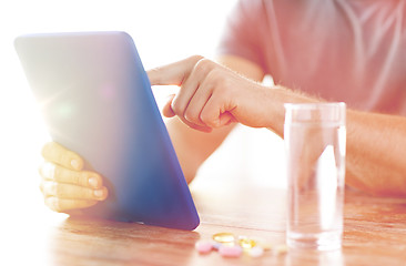 Image showing close up of hands with tablet pc, pills and water