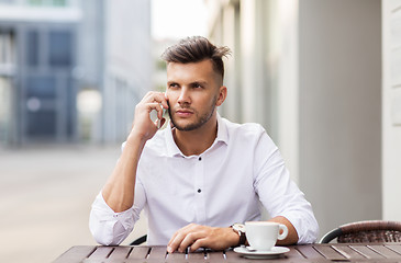 Image showing man with coffee calling on smartphone at city cafe