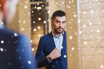 Image showing man trying jacket on at mirror in clothing store