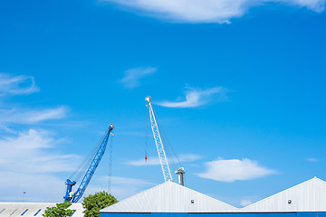 Image showing Blue and white cranes at a storage building