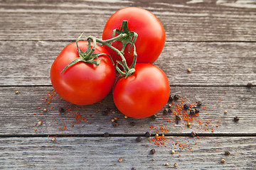 Image showing Dewy red tomatoes with pepper on old wood