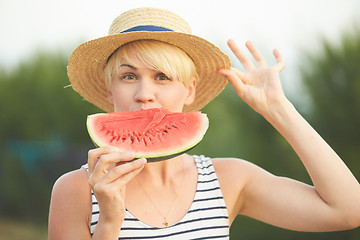 Image showing Beautiful girl in straw hat eating fresh watermelon. Film camera style